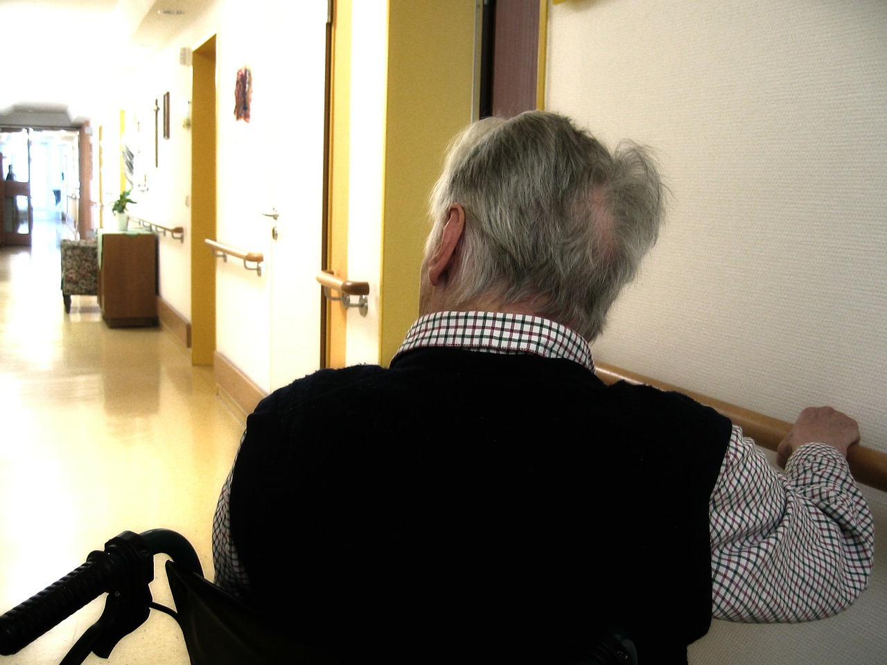 Hombre mayor en silla de ruedas en el pasillo de una residencia