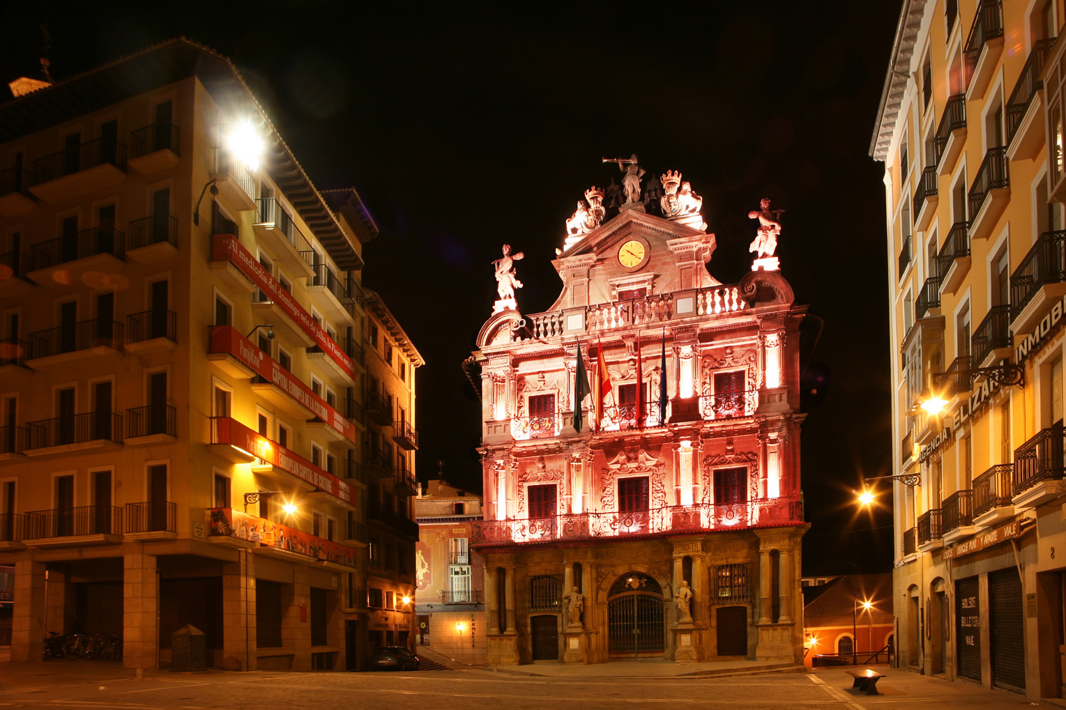 Imagen de la fachada del Ayuntamiento de Pamplona iluminada de color granate