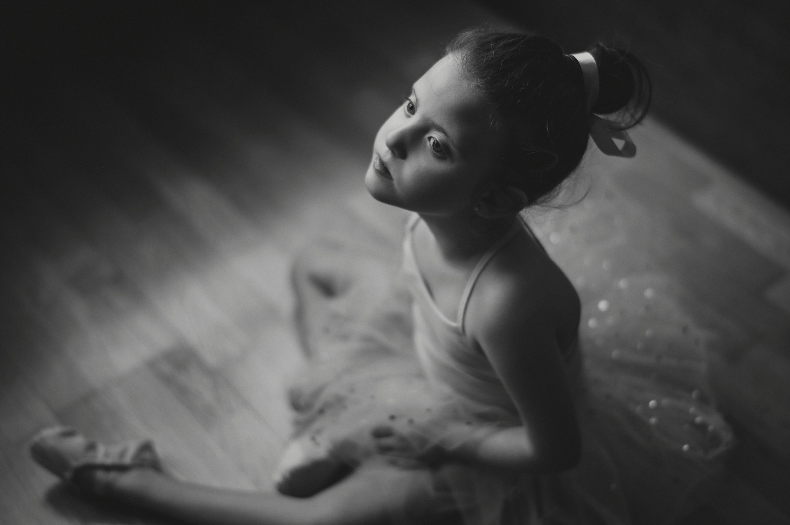 Fotografía de una niña sentada en el suelo, vestida con traje de ballet.