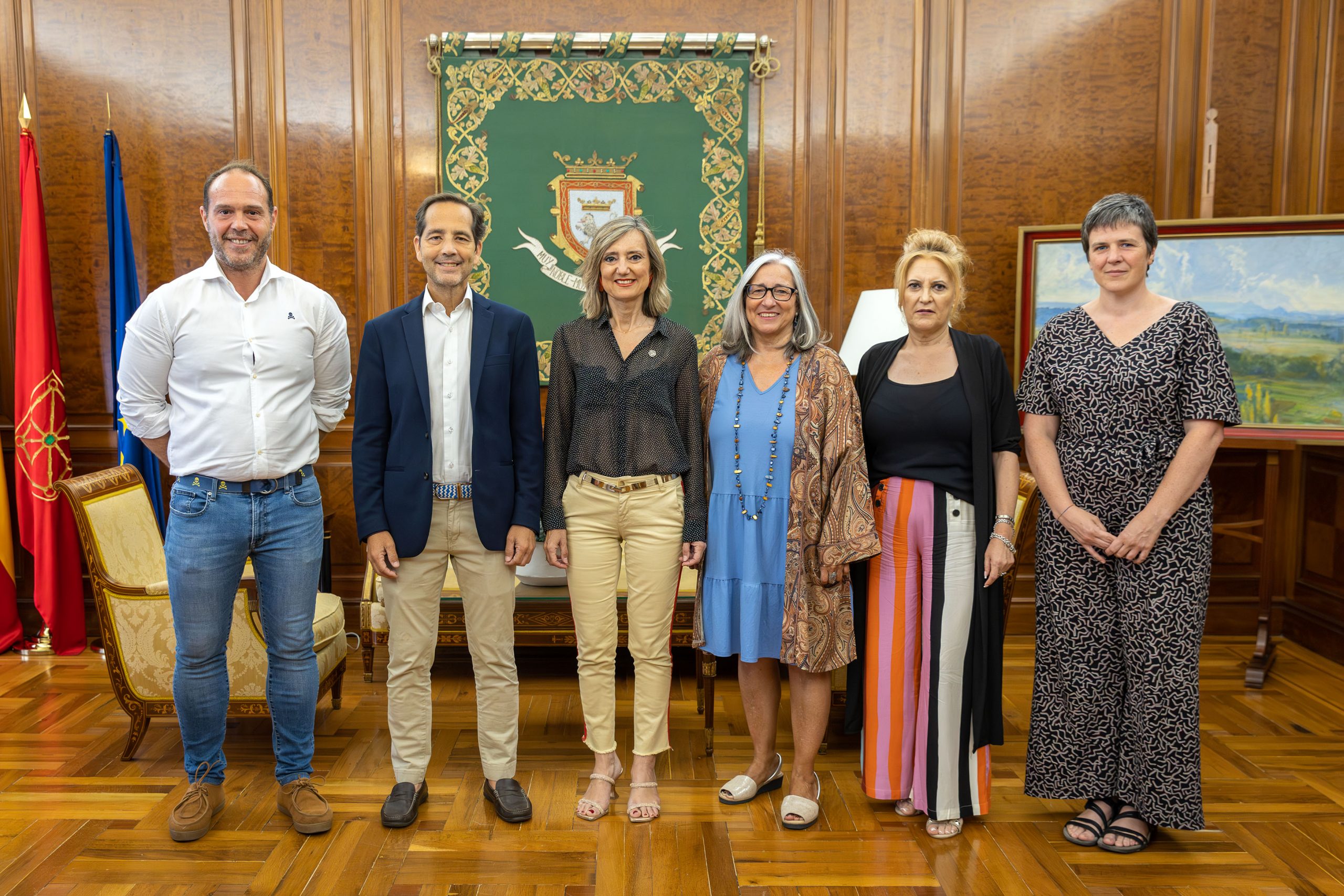Los integrantes del Ayuntamiento de Pamplona y de CERMIN que se reunieron posan en la Casa Consistorial, delante de un estandarte con el escudo de Pamplona.