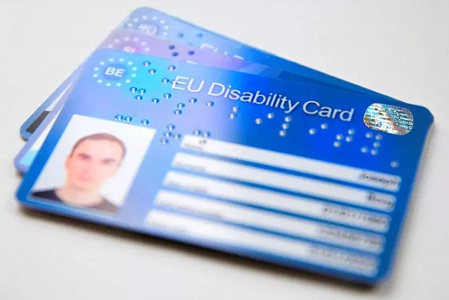 La tarjeta de la imagen es azul, con el nombre "Tarjeta Europea de Discapacidad" en inglés. Aparecen el escudo de la UE, el código del país de origen, la fotografía de la persona y sus datos personales. Utiliza también el sistema braille.