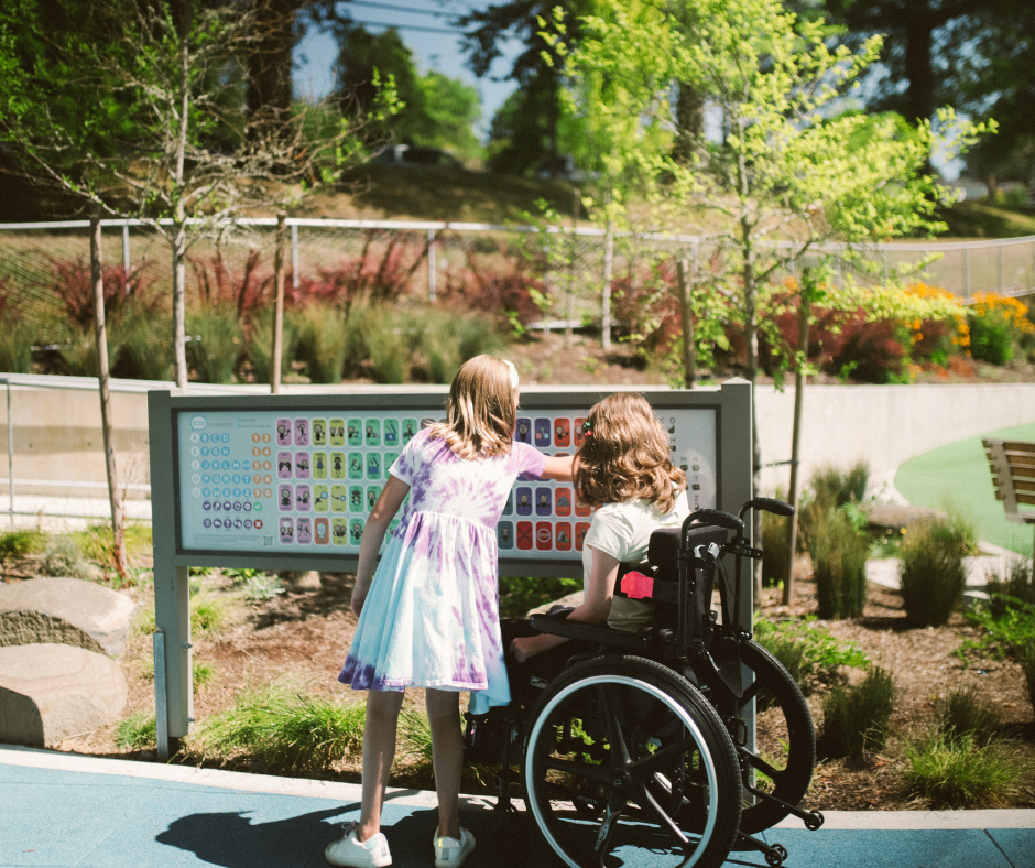 Imagen de archivo usuario de silla de ruedas viendo un panel informativa con una niña.
