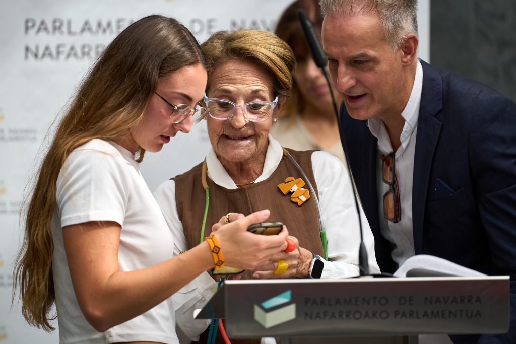 Momento de lectura del manifiesto, una chica joven sostiene el móvil que lo está viendo la persona que se encuentra a su lado de mayor edad.