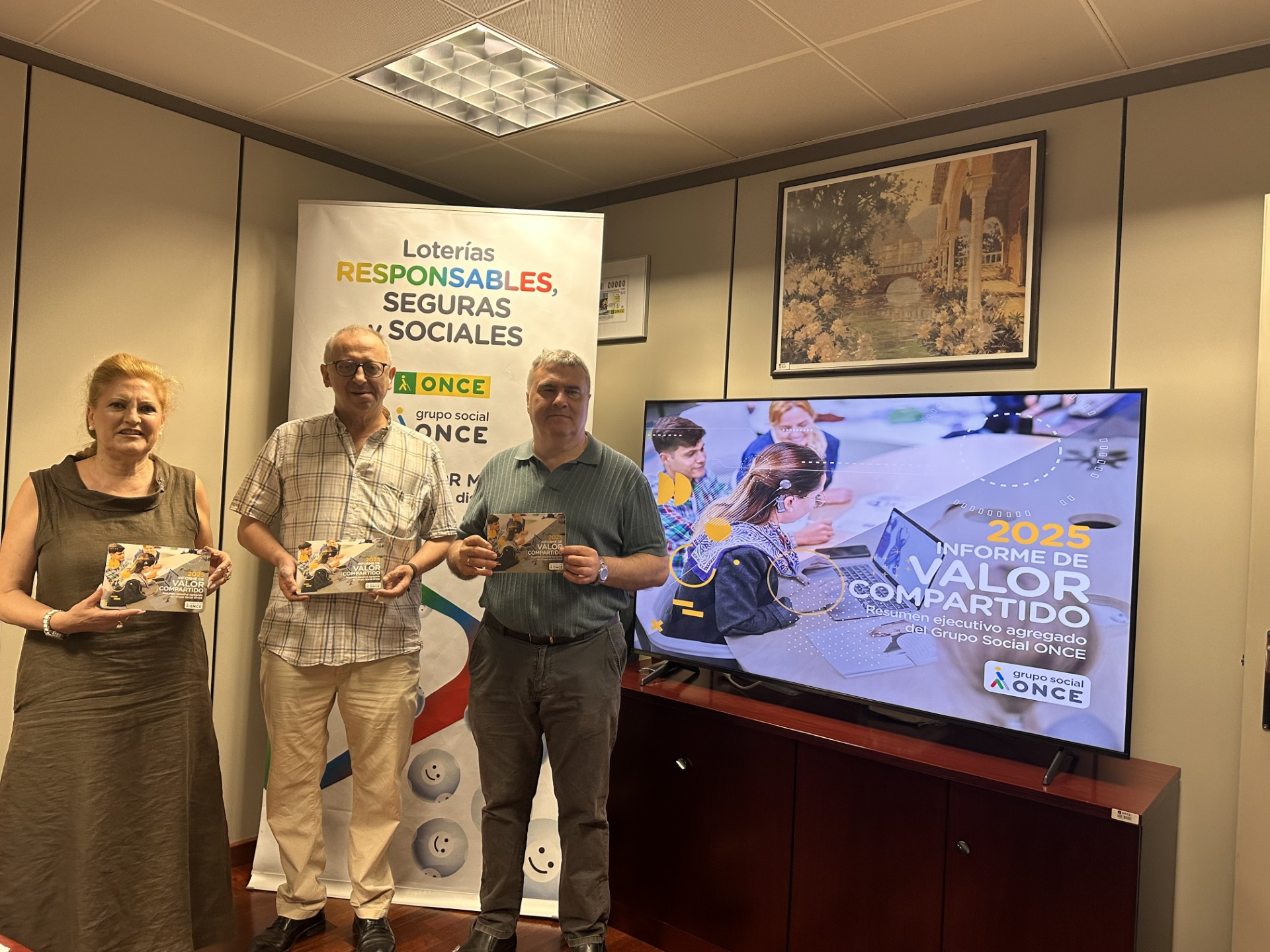 REPRESENTANTES DE ONCE NAVARRA MOSTRANDO UNA TARJETA CON LA IMAGEN DEL INFORME
