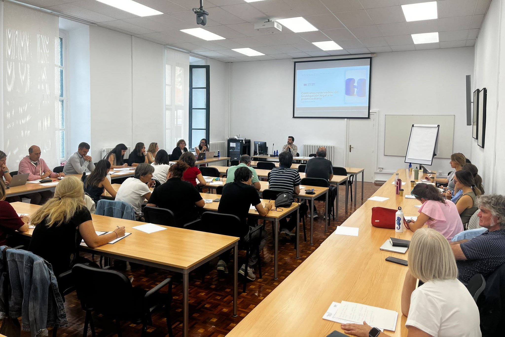 personas en un espacio de trabajo mirando una pantalla de proyección en una jornada